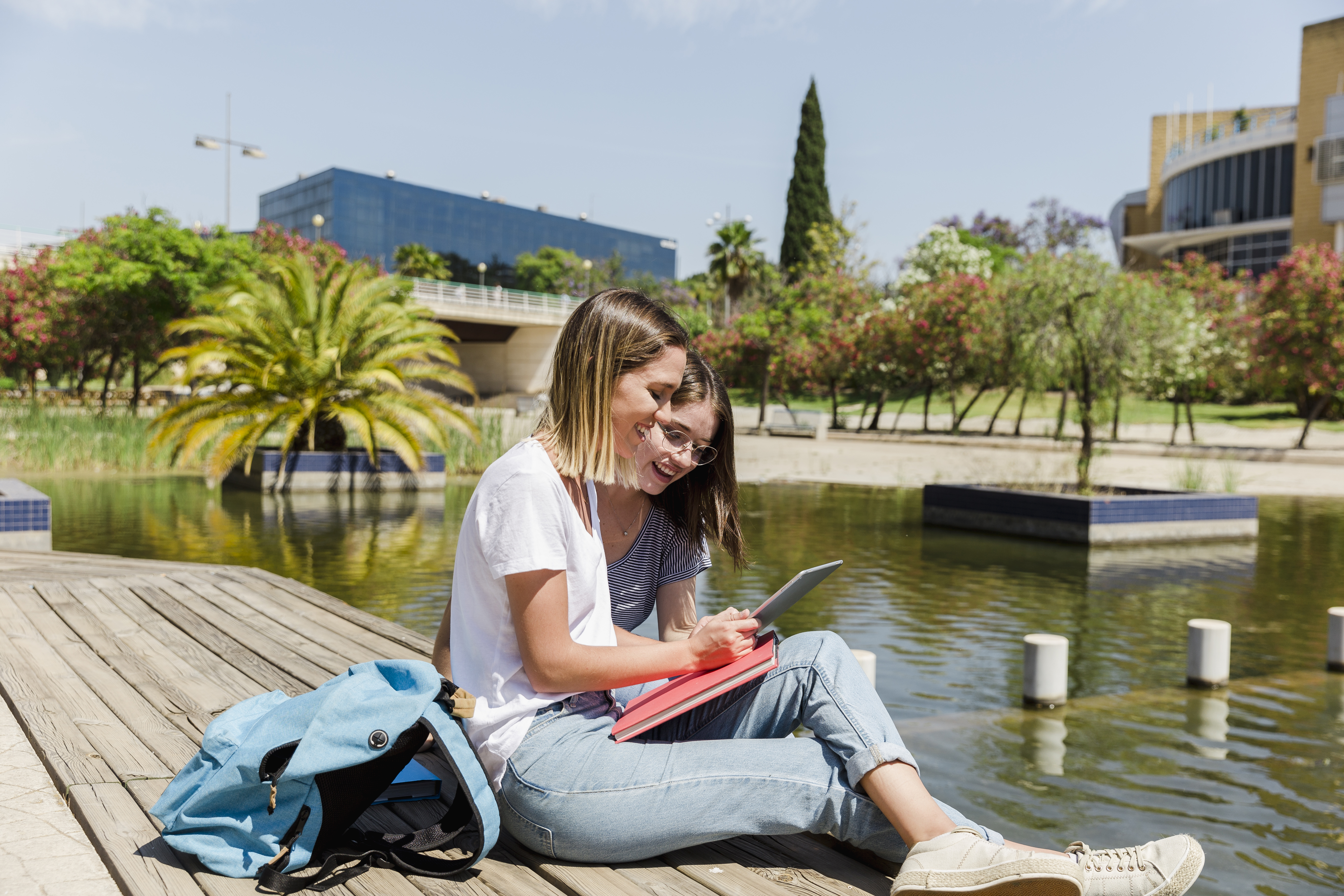 twee studenten aan het water, kijkend op de tablet 